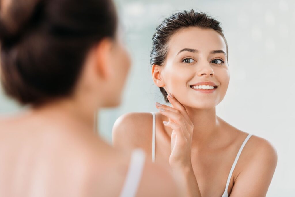 A woman looking in the mirror at her teeth.